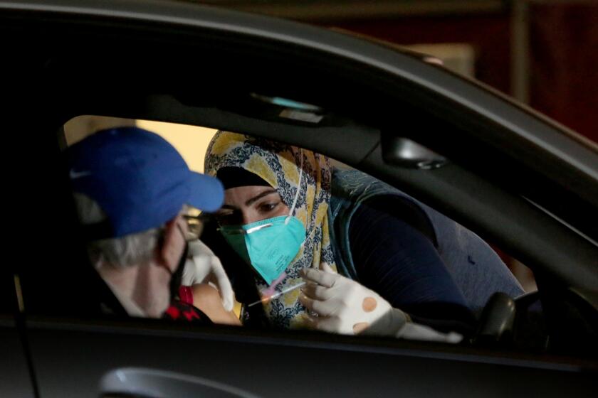 LONG BEACH, CA. - JAN. 21, 2021. Dr. Sarah Mohtadi administers coronavirus vaccine at a drive-in vaccination site at the Long Beach Convention Center on Thursday, Jan. 21, 2021. (Luis Sinco/Los Angeles Times)