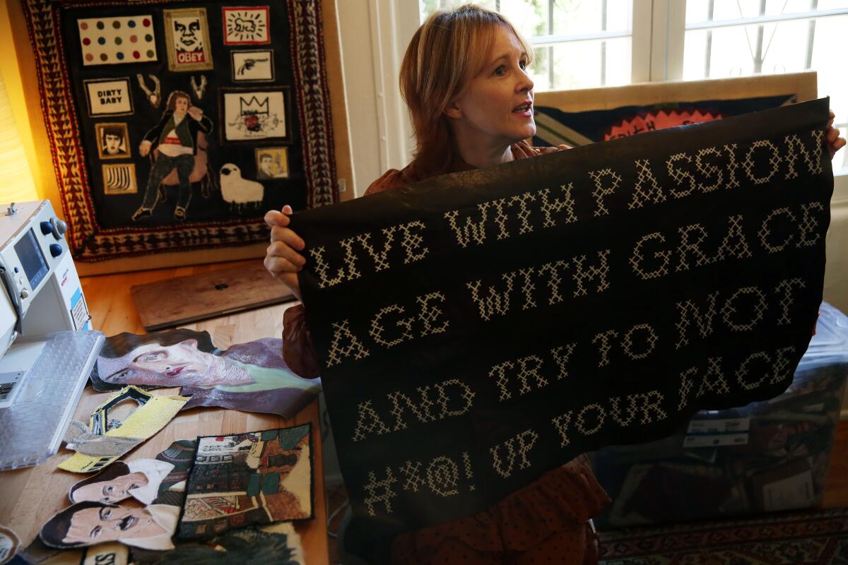 Lisa Borgnes-Giramonti holds up one of her embroidery pieces while in her home studio in Hollywood Heights