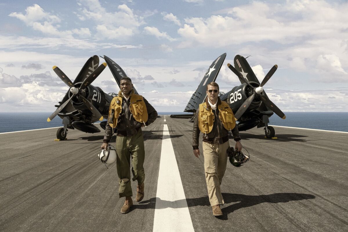 Two Navy pilots walk away from their planes on the deck of aircraft carrier in the movie "Devotion."