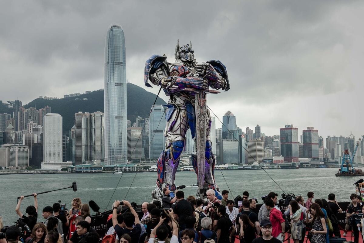 A 20-foot-tall Optimus Prime figure is surrounded by journalists before the world premiere of "Transformers 4" in Hong Kong.