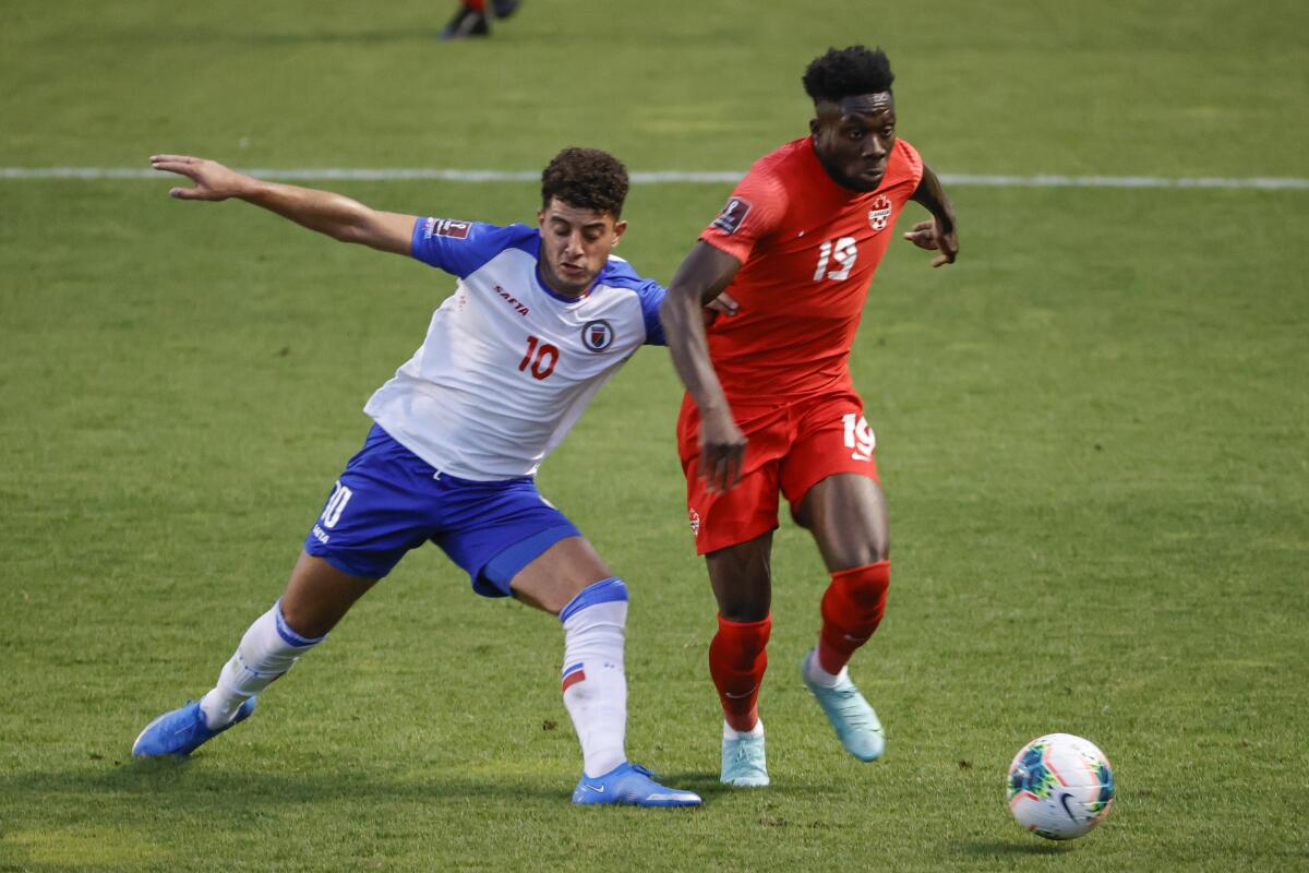 Canada's Alphonso Davies (19) goes past Haiti's Steeven Saba (10) during the first half of a World Cup qualifying soccer match Tuesday, June 15, 2021, in Bridgeview, Ill. (AP Photo/Kamil Krzaczynski)