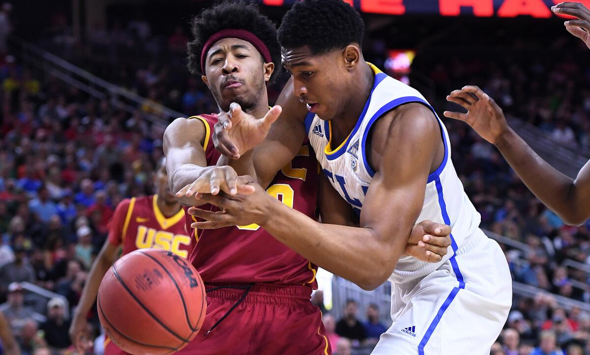 USC guard Elijah Stewart, left, and UCLA forward Ike Anigbogu battle for a loose ball during Pac-12 tournament play. The Trojans and Bruins are back in action tonight.