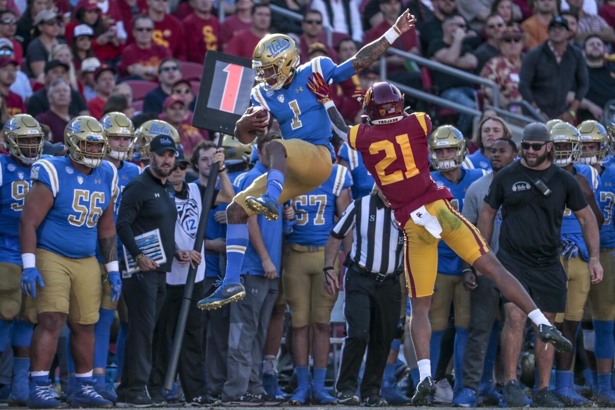 UCLA quarterback Dorian Thompson-Robinson is shoved out of bounds by by USC safety Isaiah Pola-Mao at the Coliseum on Saturday.
