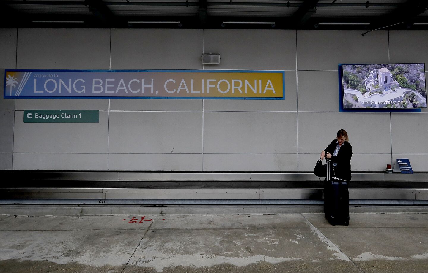 A woman claims her luggage at he Long Beach Airport.