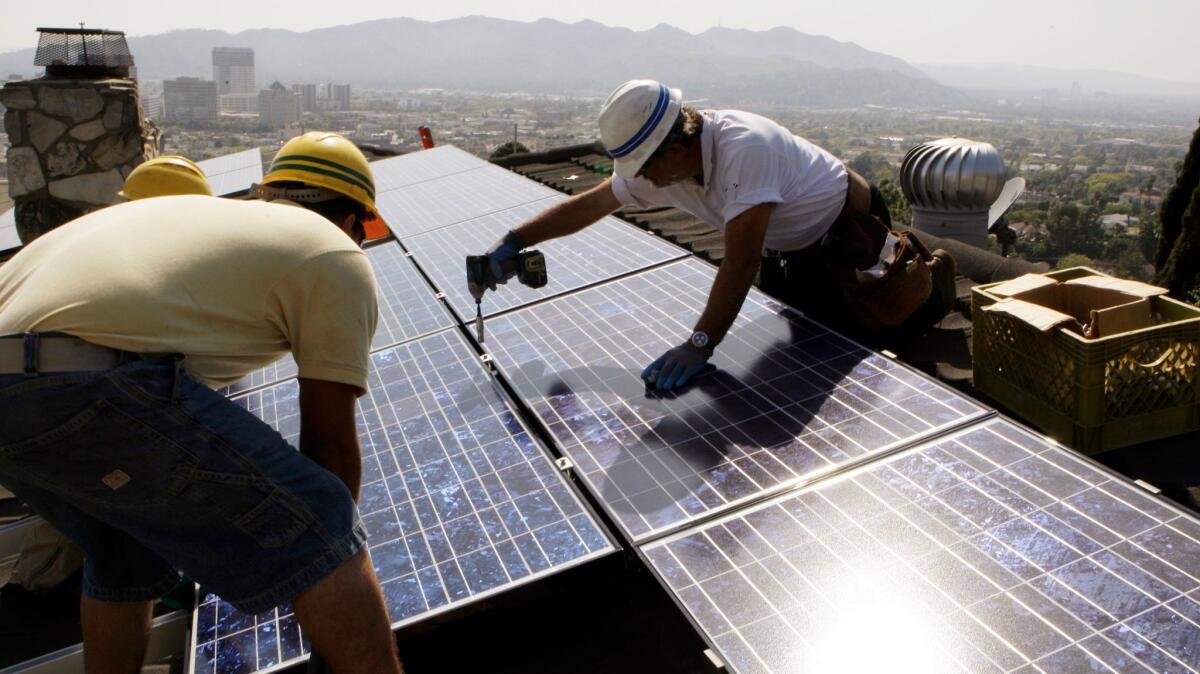 Workers install solar electrical panels on the roof of a home in Glendale, Calif. on March 23, 2010.