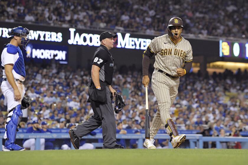San Diego Padres' Trent Grisham, right, celebrates as he heads to first after hitting a solo home run as Los Angeles Dodgers catcher Austin Barnes, left, and home plate umpire Scott Barry watch during the fifth inning of a baseball game Friday, July 1, 2022, in Los Angeles. (AP Photo/Mark J. Terrill)
