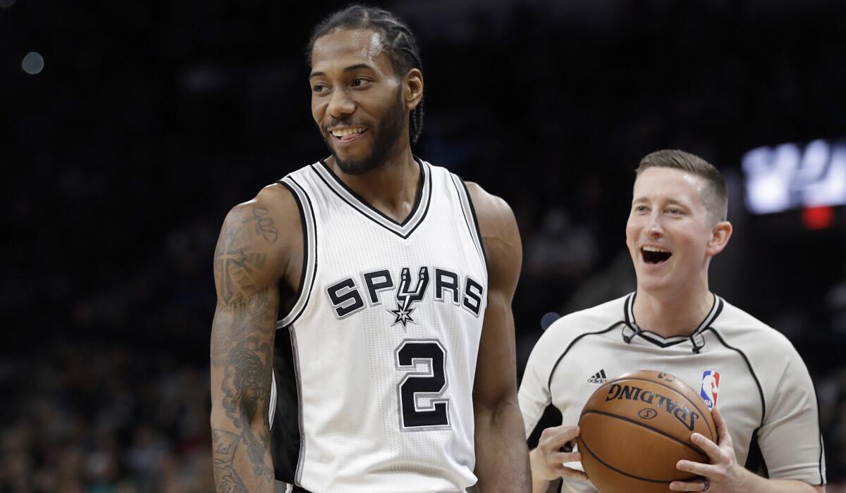 San Antonio Spurs forward Kawhi Leonard (2) and referee Nick Buchert (3) share a laugh during the first half of a game against the Toronto Raptors on Tuesday.