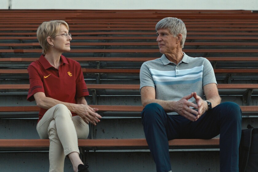 Angela Nicholas and Matthew Modine sit on bleachers.