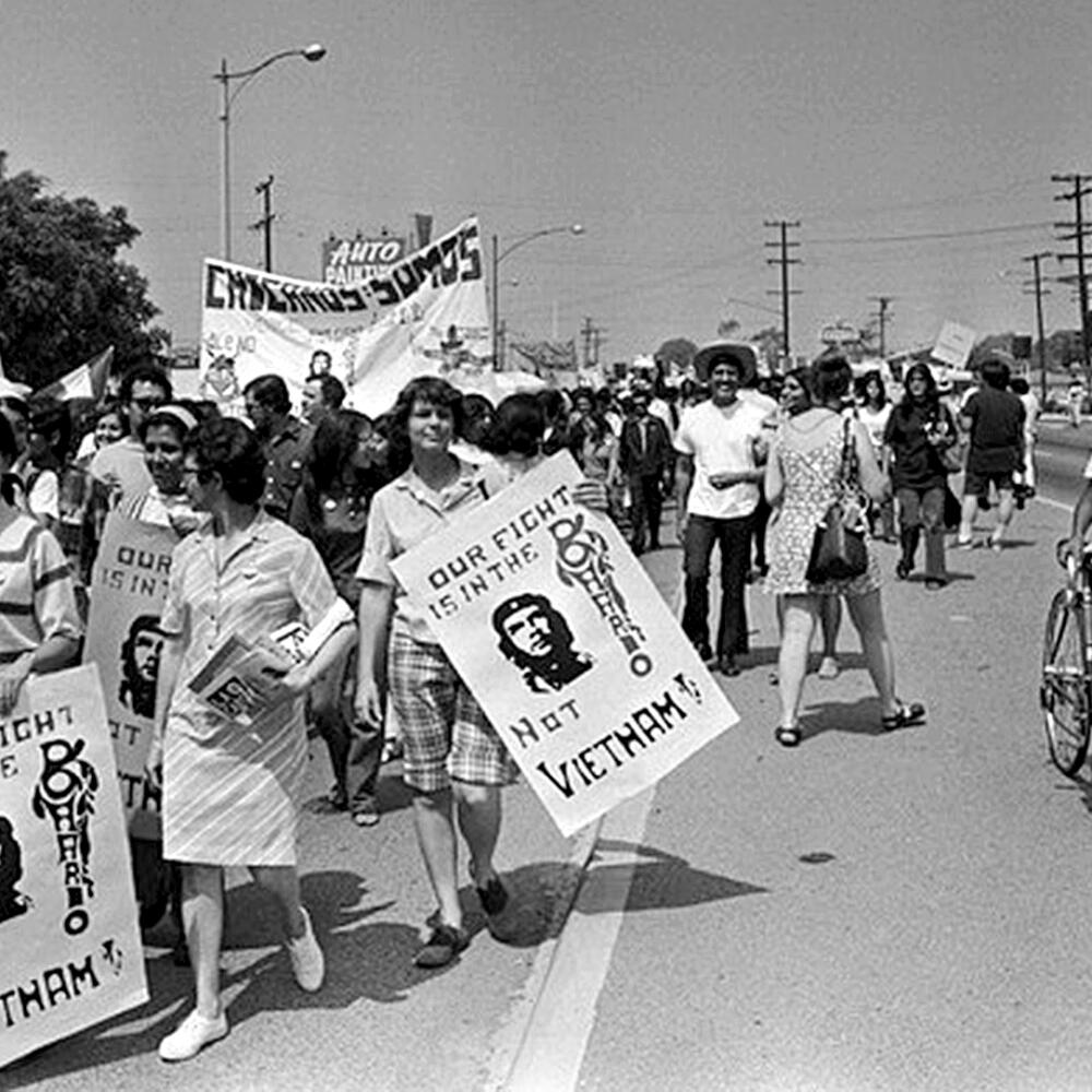 People walk down a road, some holding big placards.