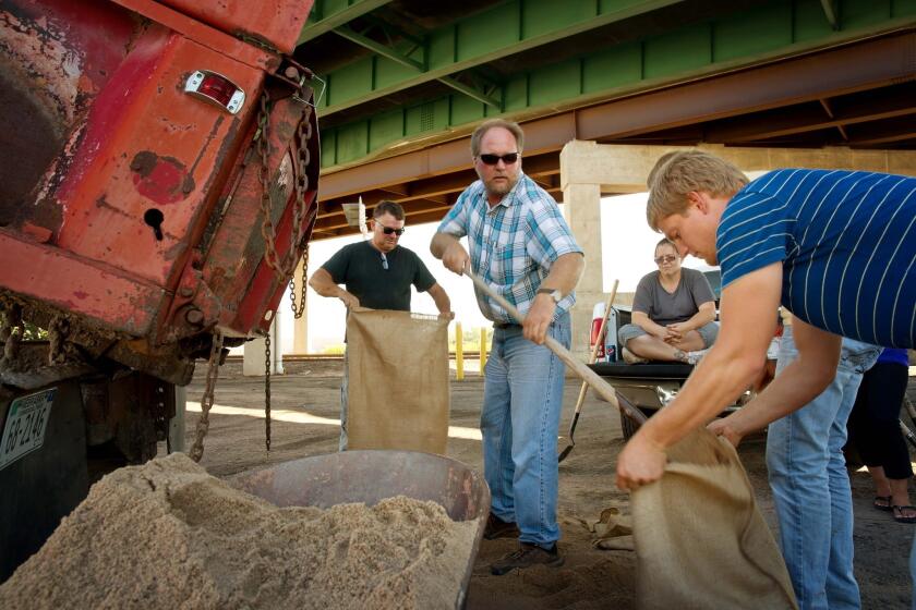 Tim Unruh, of Paxton, Neb., center, shovels sand into a bag as residents fill sandbags along the South Platte River in Ogallala, Neb. Colorado floodwaters were flowing into the state Wednesday, with some flooding in rural areas.