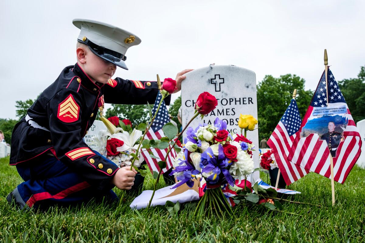 Christian Jacobs, 7, of Hertford, N.C., tends the gravesite of his father, Marine Sgt. Christopher Jacobs, at Arlington National Cemetery.
