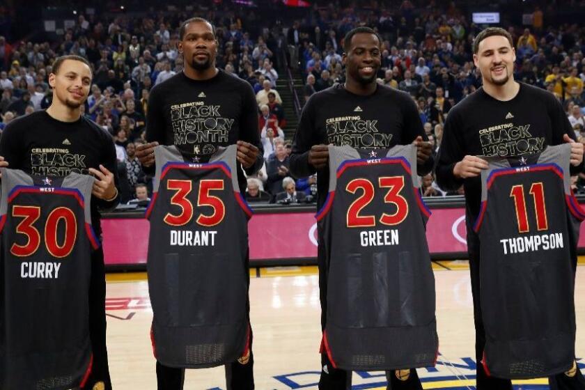 Golden State Warriors, from left to right, Stephen Curry, Kevin Durant, Draymond Green, and Klay Thompson hold up their NBA All-Star jersey's during a pre-game ceremony on Feb. 15.