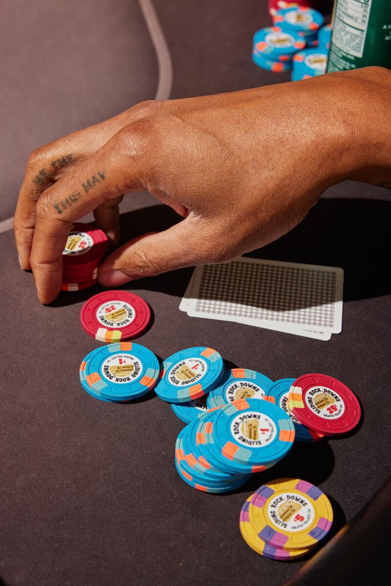 Poker chips splayed on a table, a hand hovering over a few red chips. 