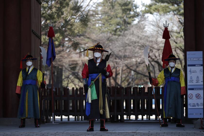Officials wearing traditional guard uniforms and masks stand in front of the Deoksu palace in downtown Seoul, South Korea, Sunday, Feb. 23, 2020. South Korea and China both reported a rise in new virus cases on Sunday, as the South Korean prime minister warned that the fast-spreading outbreak linked to a local church and a hospital in the country's southeast had entered a "more grave stage." (AP Photo/Lee Jin-man)
