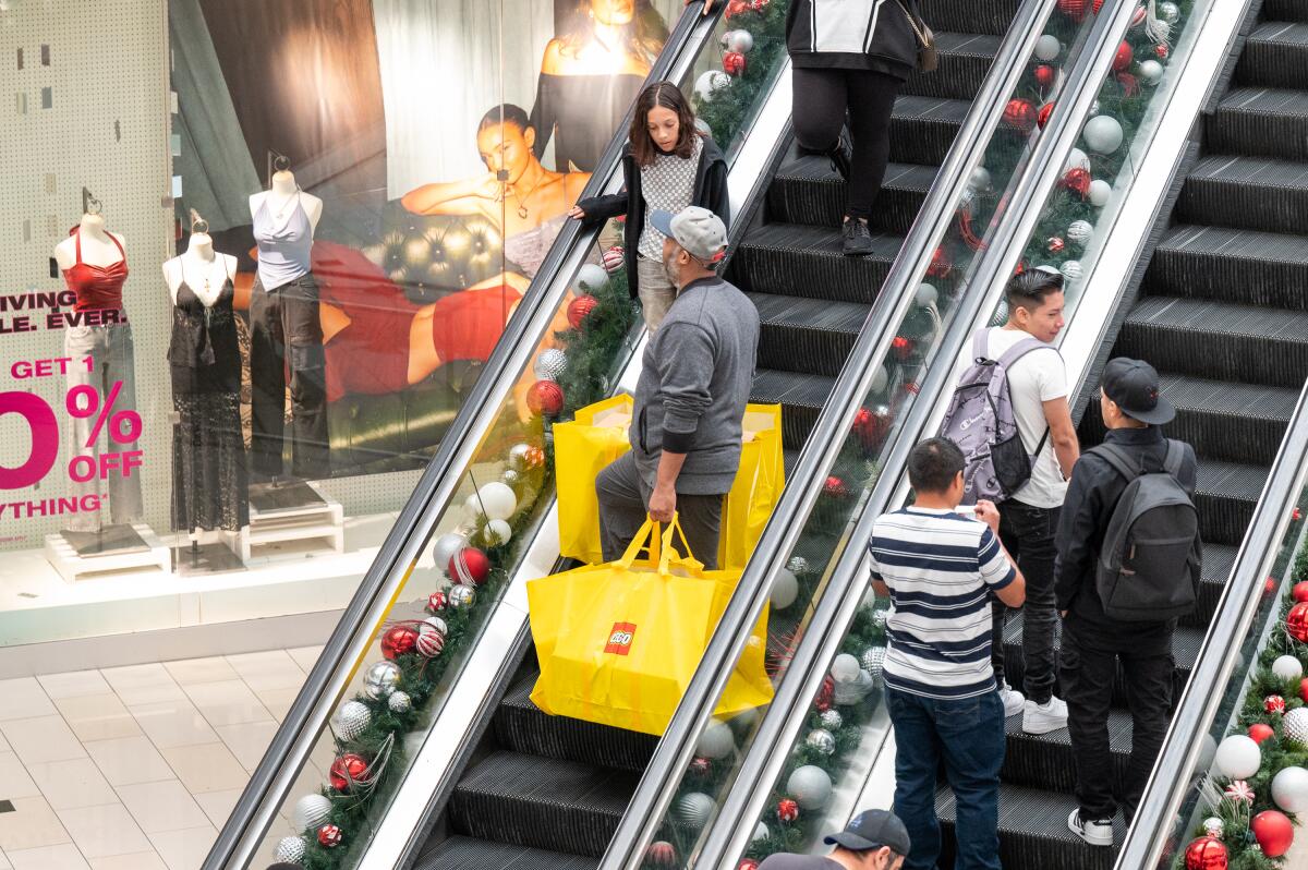 Shoppers ride escalators at a mall.