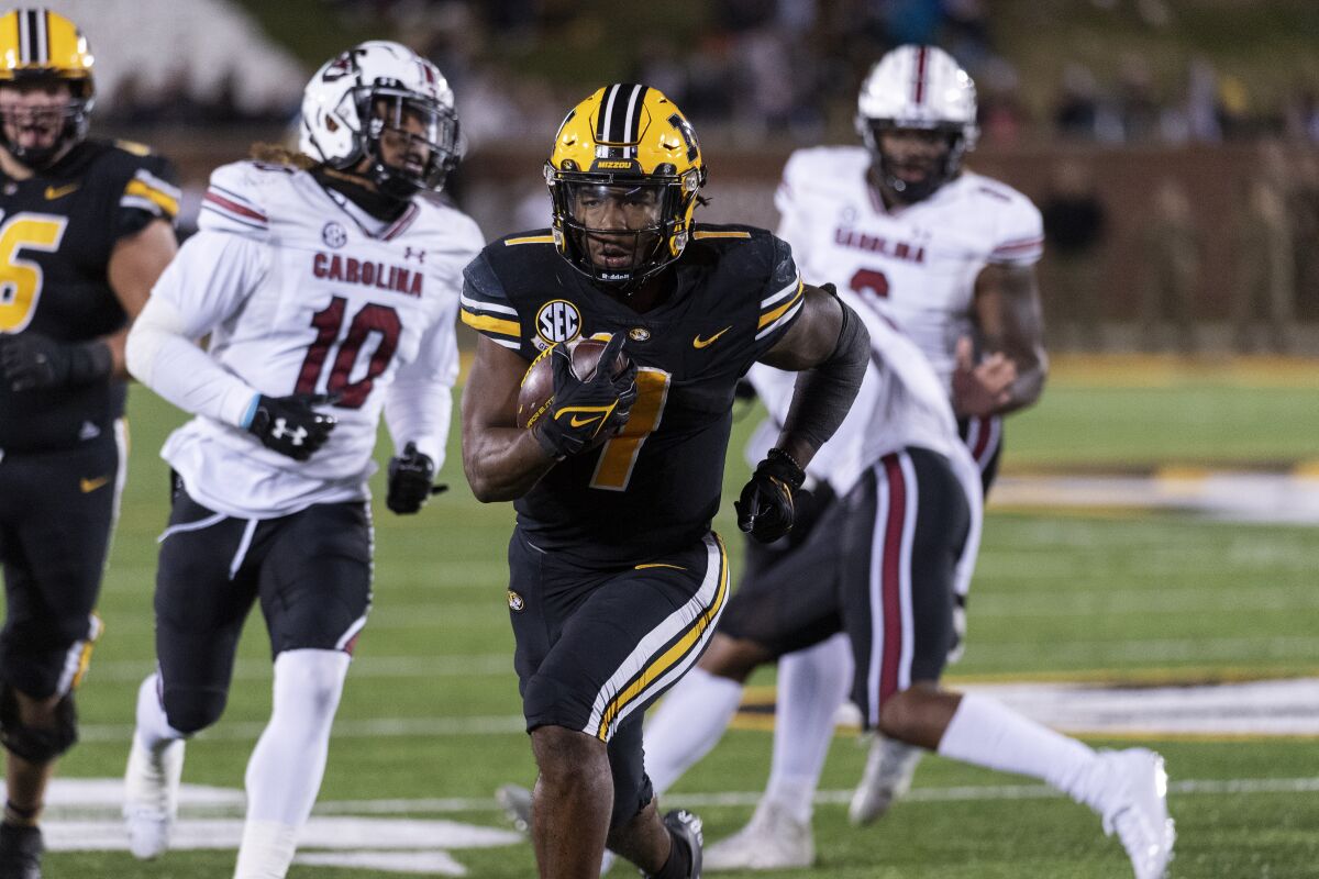 Missouri running back Tyler Badie, center, scores a touchdown in front of South Carolina defensive back R.J. Roderick, left, and defensive lineman Zacch Pickens, right, during the fourth quarter of an NCAA college football game Saturday, Nov. 13, 2021, in Columbia, Mo. Missouri won 31-28.(AP Photo/L.G. Patterson)
