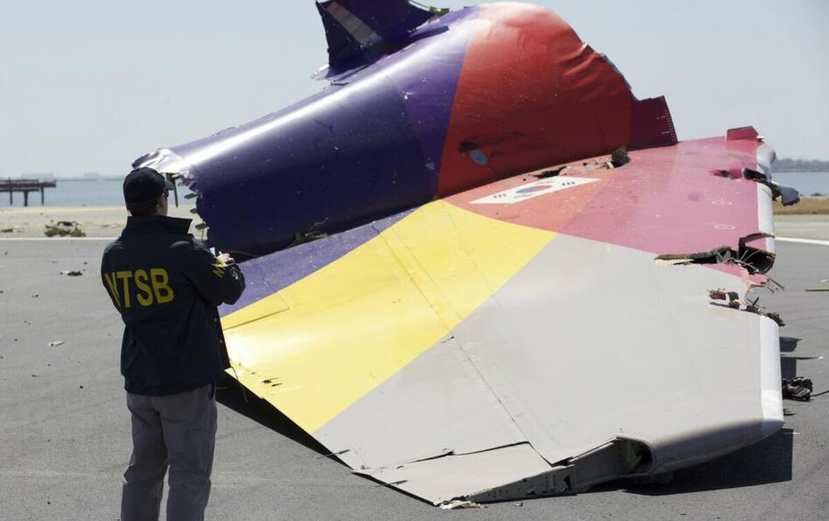 An NTSB investigator looks at the tail section of Asiana Flight 214 in San Francisco.