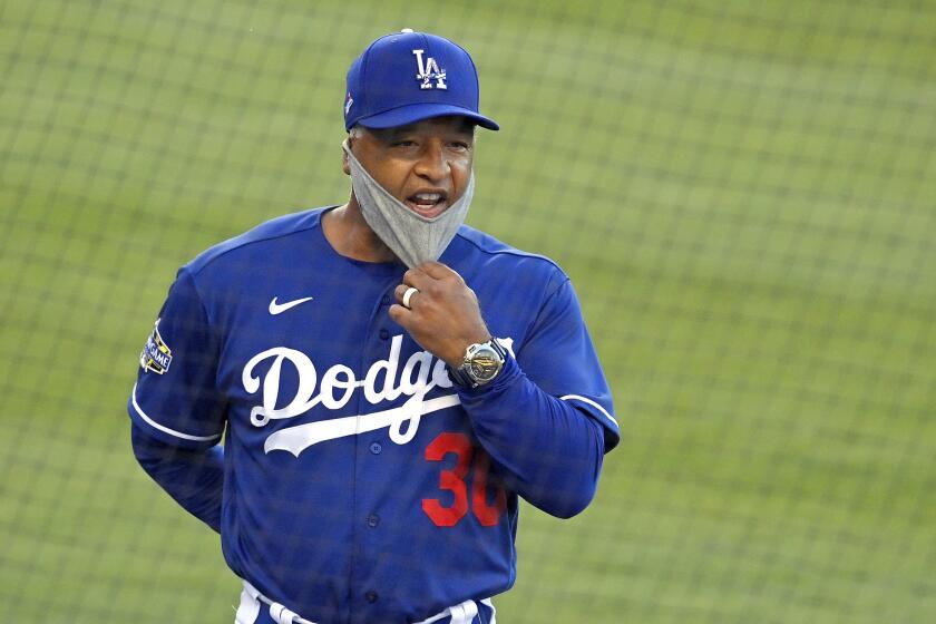 FILE - In this July 8, 2020, file photo, Los Angeles Dodgers manager Dave Roberts pulls down his mask.