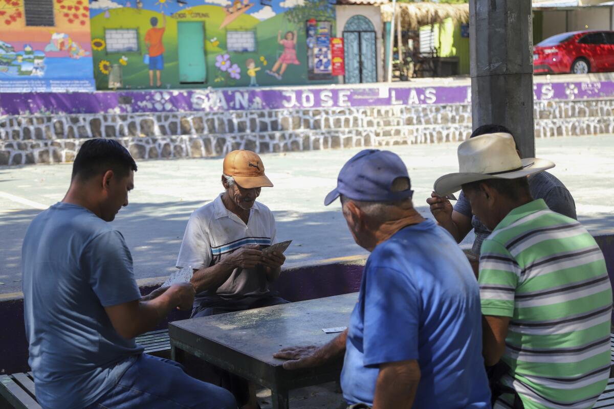 Vecinos juegan a las cartas en el parque central de San José Las Flores