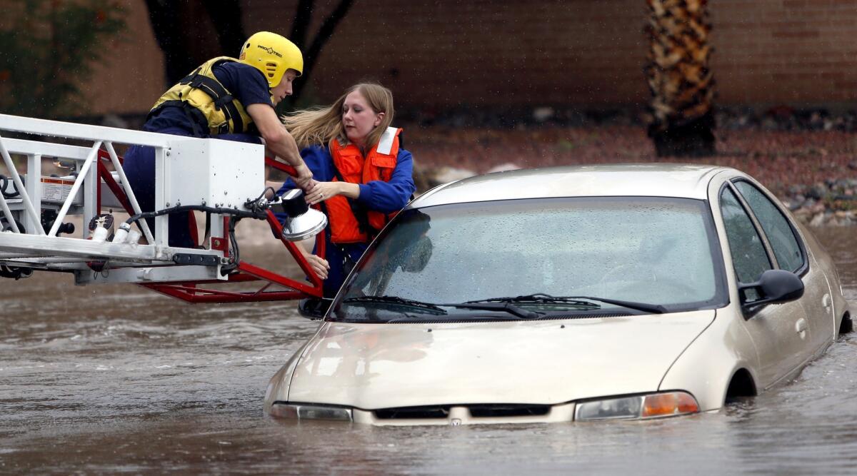 A Tucson Fire Department rescuer uses a ladder truck to help a woman from a car in east Tucson.