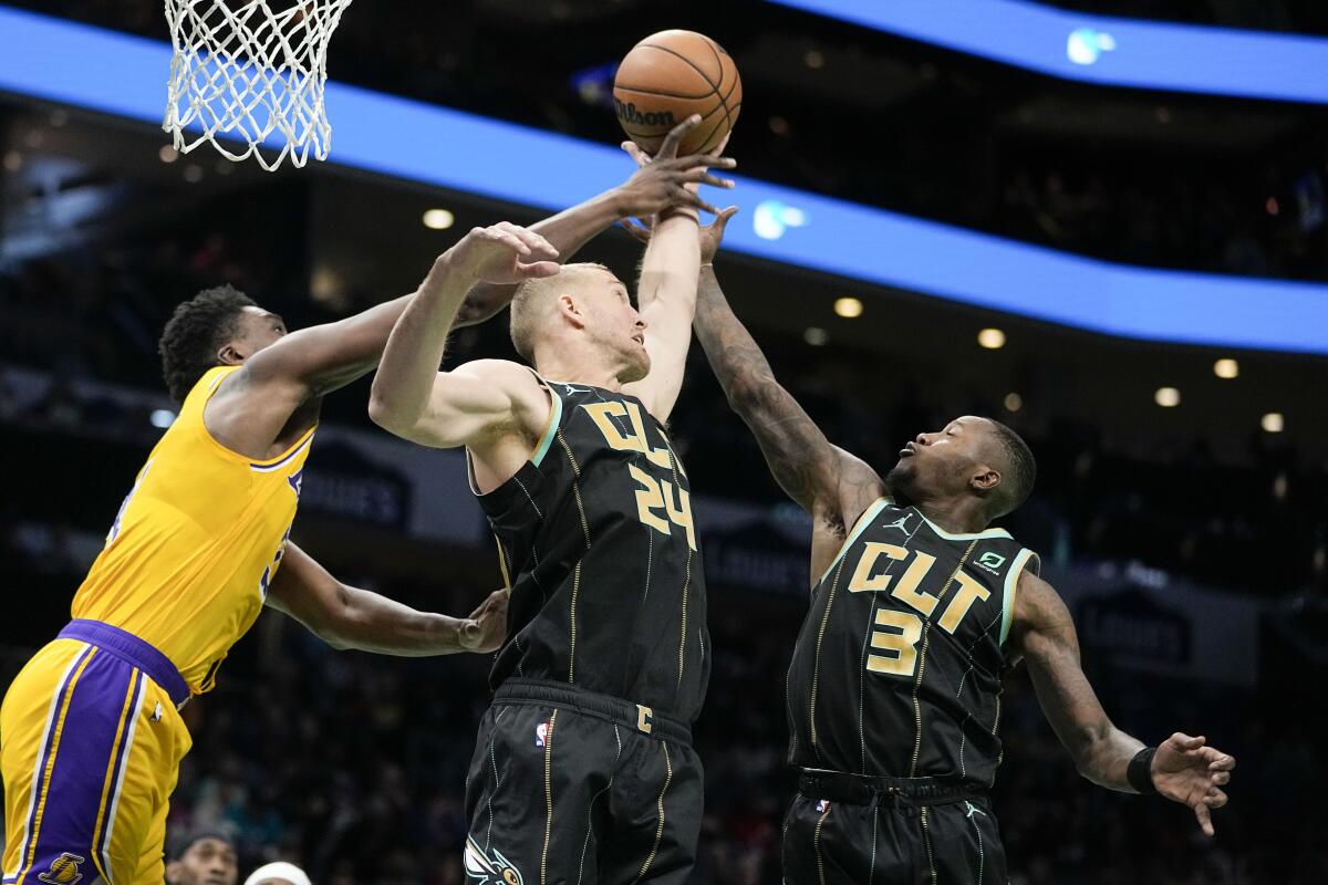 Lakers center Thomas Bryant vies for the ball with Charlotte Hornets center Mason Plumlee and guard Terry Rozier.