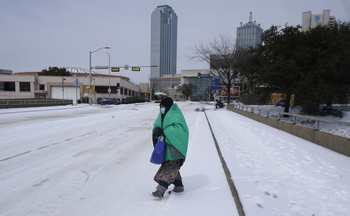 A woman wrapped in a blanket crosses the street near downtown Dallas