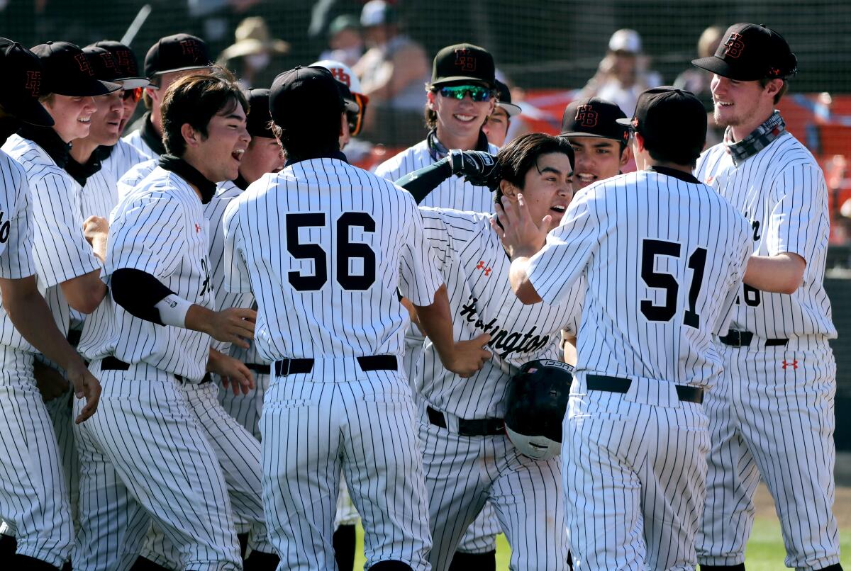 Caden Aoki of Huntington Beach High baseball, center, celebrates with teammates after hitting a home run against Edison.