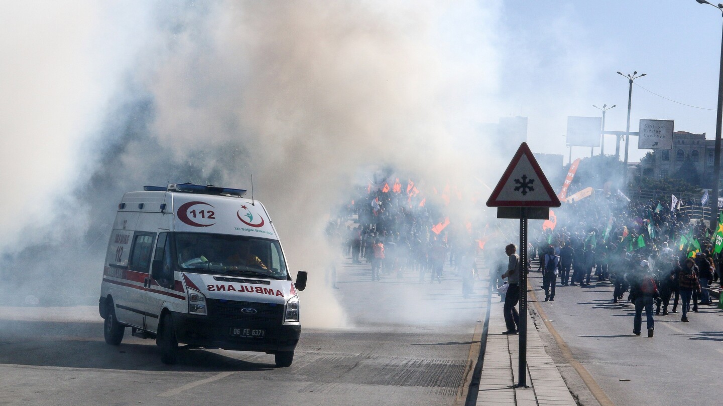 An ambulance carrying leaves the scene as smoke rises from the scene after a pair of explosions at a peace rally in Ankara, Turkey.