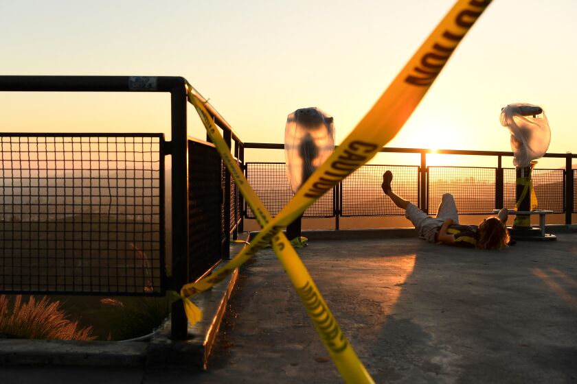 LOS ANGELES, CALIFORNIA APRIL 28, 2020-A man relaxes next to caution tape at Griffith Observatory during a clear day as the city remains locked down because of the coronavirus outbreak. (Wally Skalij/Los Angeles Times)