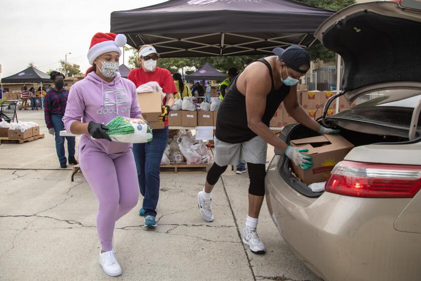SAN DIEGO, CA - DECEMBER 23: Lorraine Ward, Lane Hollerbach and Claude Edwards load food into cars during a drive-thru distribution event on Wednesday, Dec. 23, 2020 at Bayview Church in San Diego, CA. (Jarrod Valliere / The San Diego Union-Tribune)