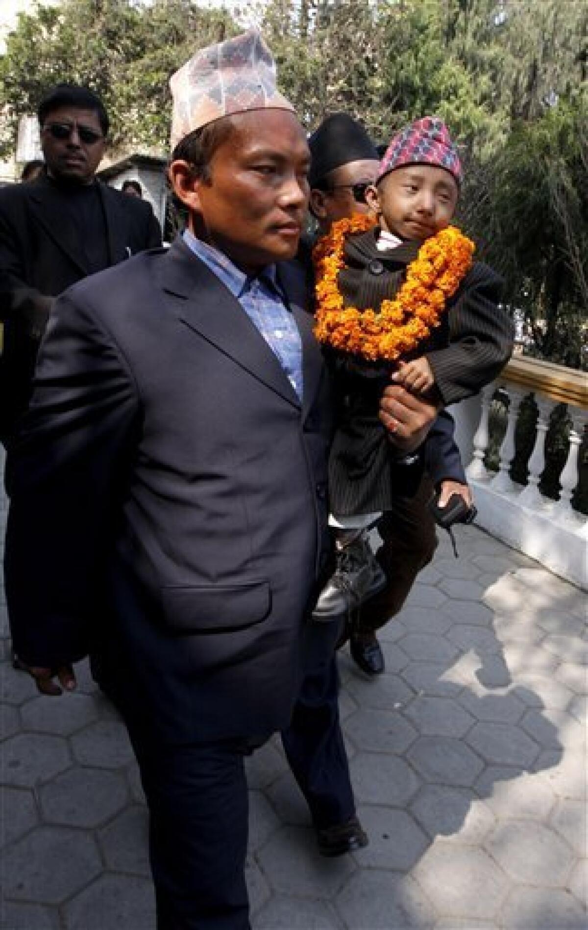 Khagendra Thapa Magar, 18, who stands at 22 inches (56 centimeters) tall, is carried by his father Rup Bahadur Thapa Magar, as he arrives for a meeting with media before leaving for Europe in Katmandu, Nepal, Sunday, Feb. 21, 2010. Magar's family initially filed a claim for the title of the world's shortest man when he was just 14 years old but it was rejected since he was not an adult and there was a chance he might grow, said Min Bahadur Ranamagar, of the Khagendra Thapa Magar Foundation. Magar turned 18 in October 2009. (AP Photo/Binod Joshi)
