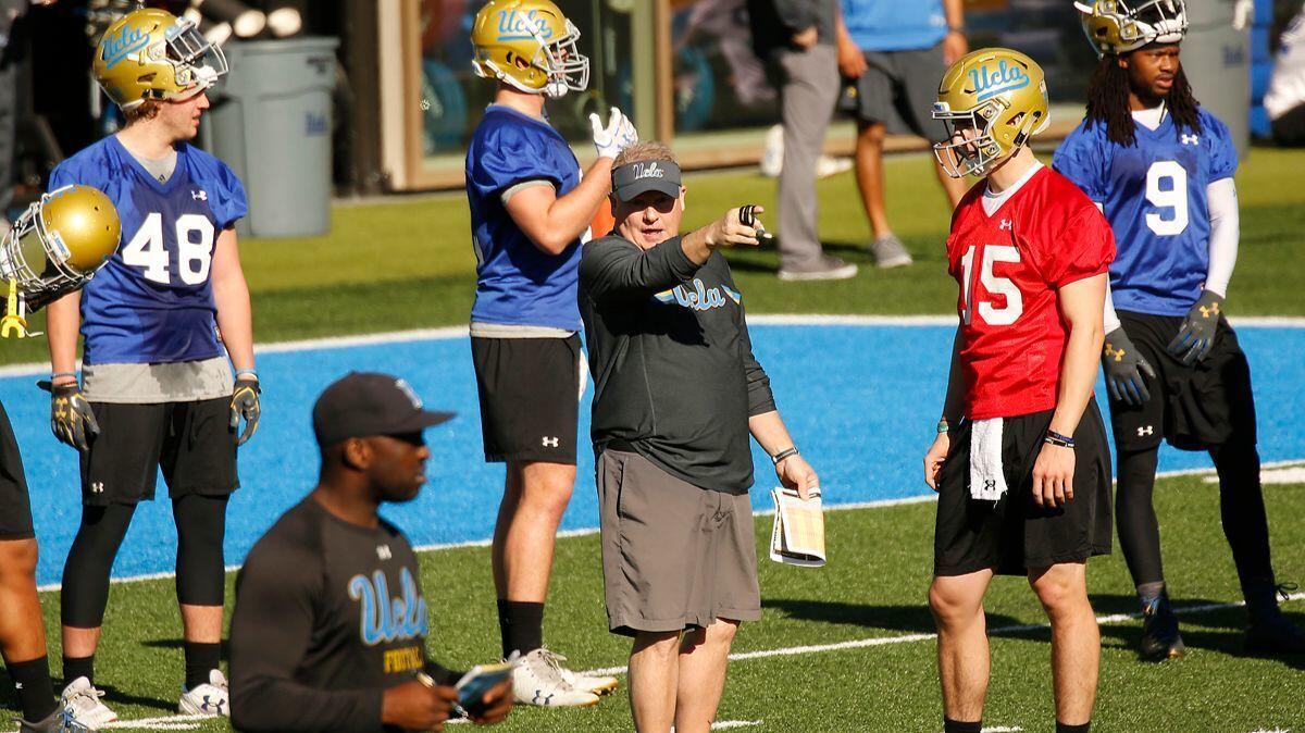 UCLA Football coach Chip Kelly, center, works with one of his quarterbacks Matt Lynch, #15, right, on the Spaulding practice field on the UCLA Westwood campus Tuesday morning.