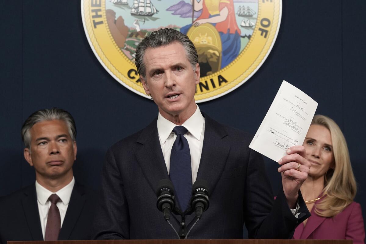 FILE - California Gov. Gavin Newsom displays a bill he signed that shields abortion providers and volunteers in California from civil judgements from out-of-state courts during a news conference in Sacramento, Calif., Friday, June 24, 2022. Newsom on Friday, Nov. 4, 2022 posthumously pardoned abortion rights activist Laura Minor, who was convicted in 1949 of abortion and conspiracy to commit abortion. She was sentenced to four yours in prison on the twin felonies and died in 1976. (AP Photo/Rich Pedroncelli, File)