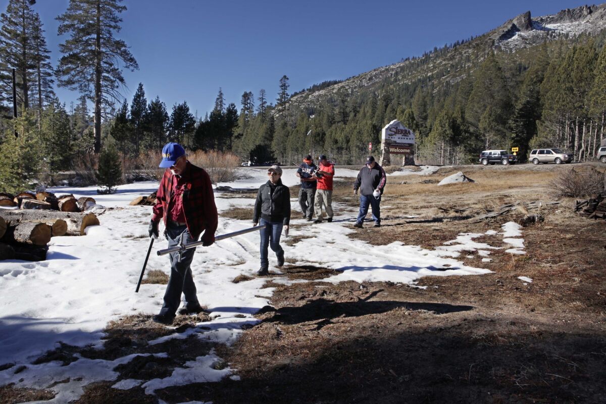 Frank Gehrke, chief of snow surveys for the California Department of Water Resources, left, walks over bare ground on the way to measuring the snowpack near Echo Summit in the Sierra Nevada. Statewide, the snowpack is just 20% of average for this time of year.