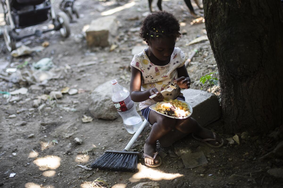 Una niña come mientras aguarda la distribución de alimentos,