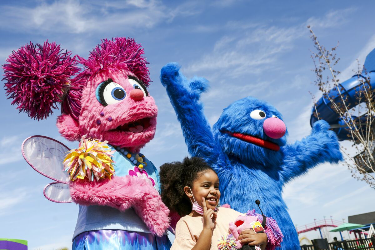 Sesame Street characters pose with a smiling girl