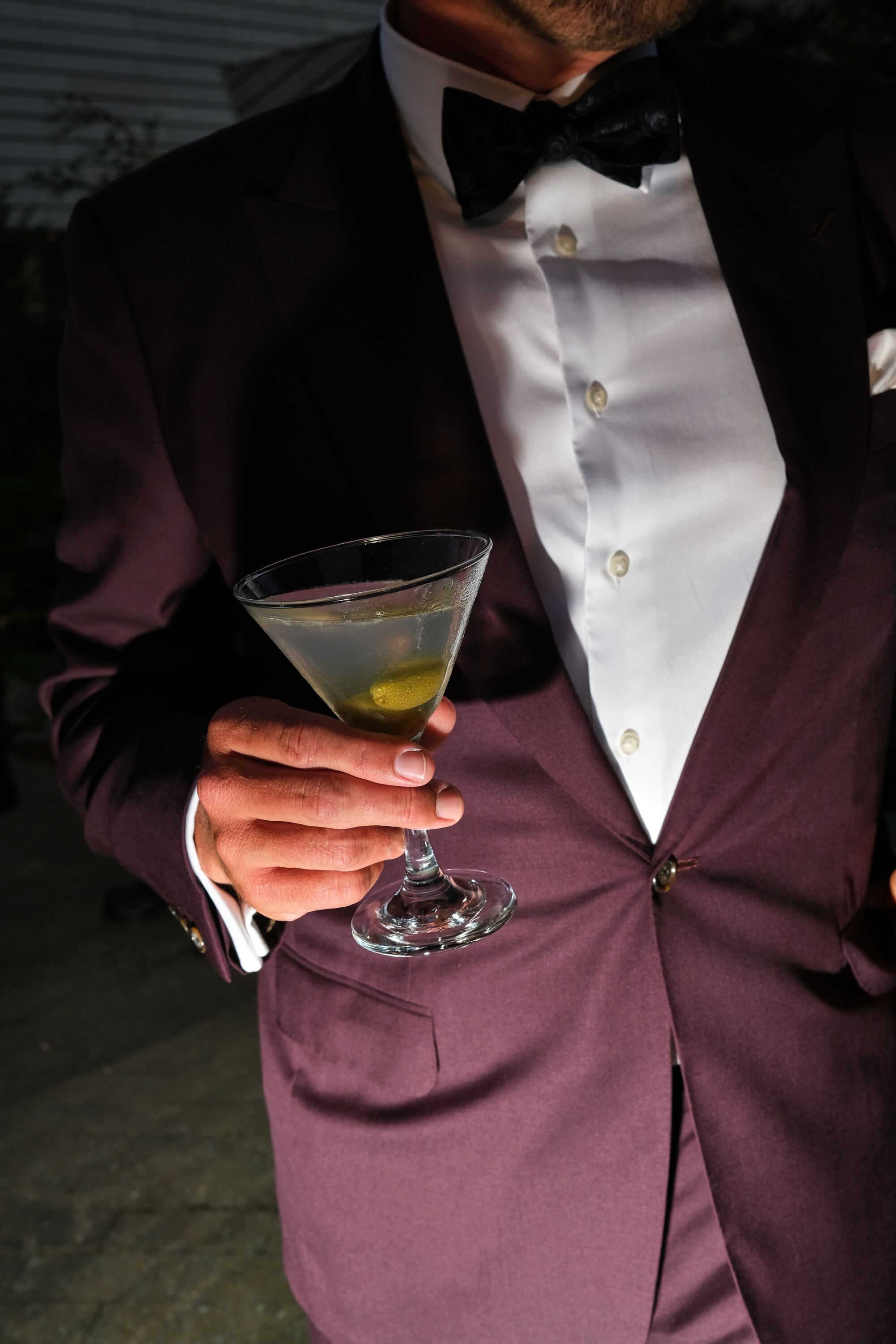 A person in a purple tuxedo is holding a martini.