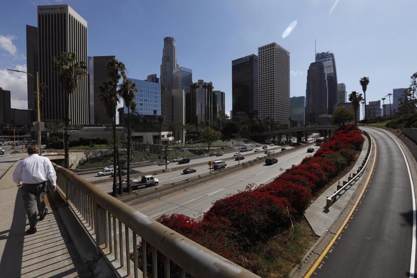 LOS ANGELES, CA - MARCH 11, 2020 - A pedestrian makes his way over noticeably light traffic on the I-110 Harbor Freeway and exit lanes around 3:30 p.m. in downtown Los Angeles on March 11, 2020. (Genaro Molina / Los Angeles Times)