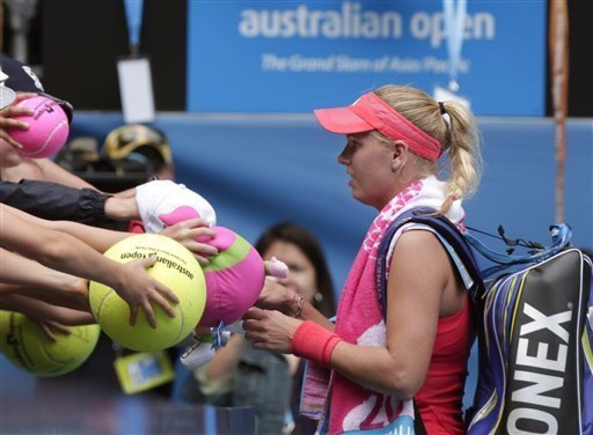 Caroline Wozniacki of Denmark signs autographs for fans after beating Georgia's Anna Tatishvili during their second round match at the Australian Open tennis championship, in Melbourne, Australia, Wednesday, Jan. 18, 2012. (AP Photo/Rick Rycroft)