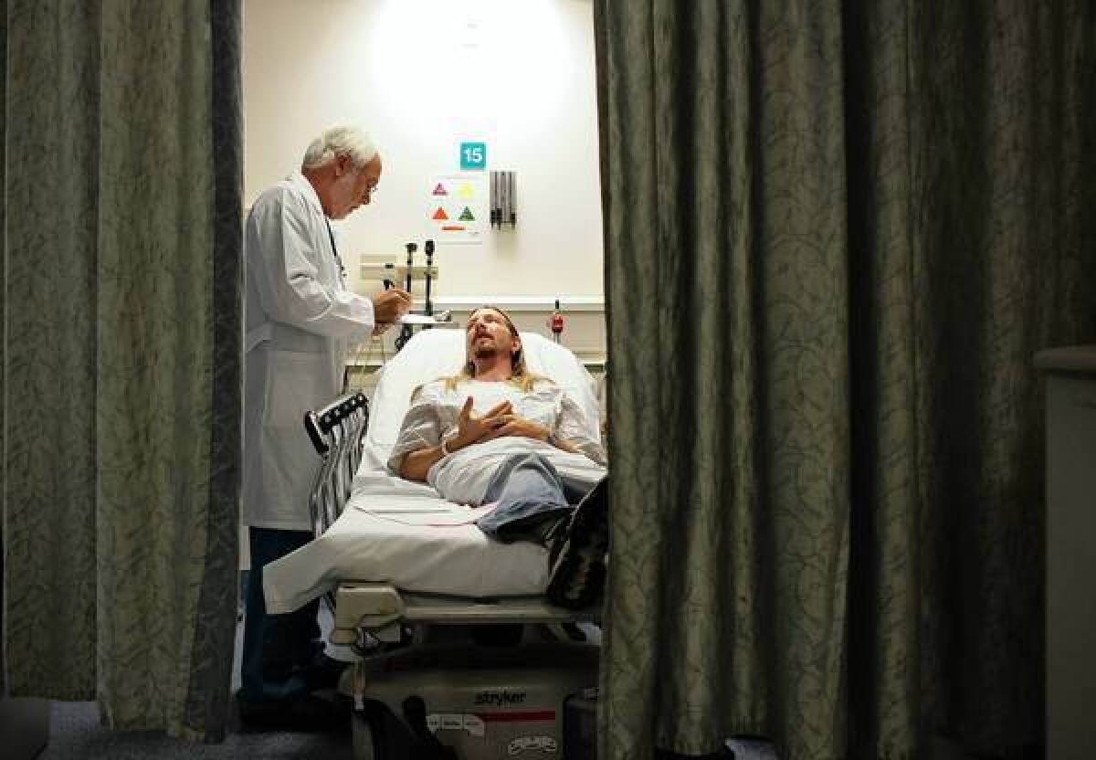 Dr. Philip Schwarzman examines a patient at Providence St. Joseph Medical Center in Burbank. Unanticipated costs associated with the Affordable Care Act could present major pitfalls for California.