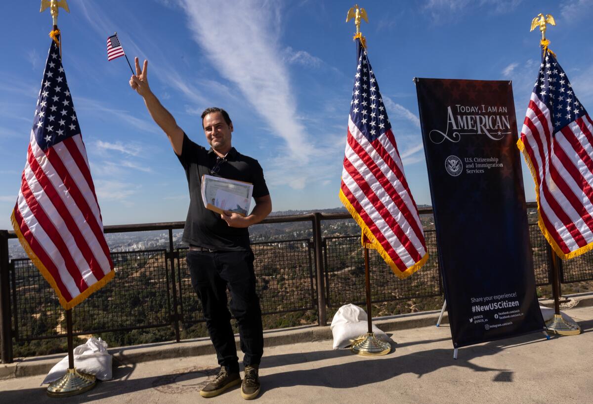 A man poses for a photo while holding the peace sign up with one hand