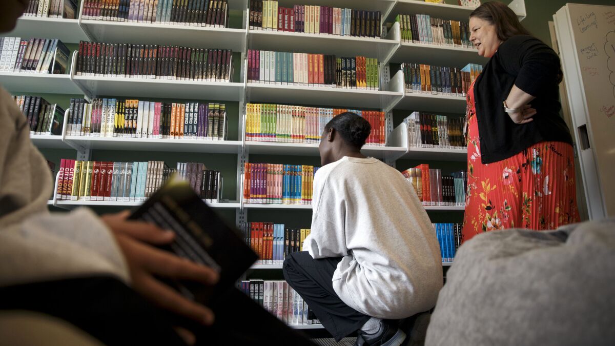 Amy Trulock, right, a full-time on-site librarian, watches as the girls browse the shelves inside the Los Padrinos Juvenile Hall library.