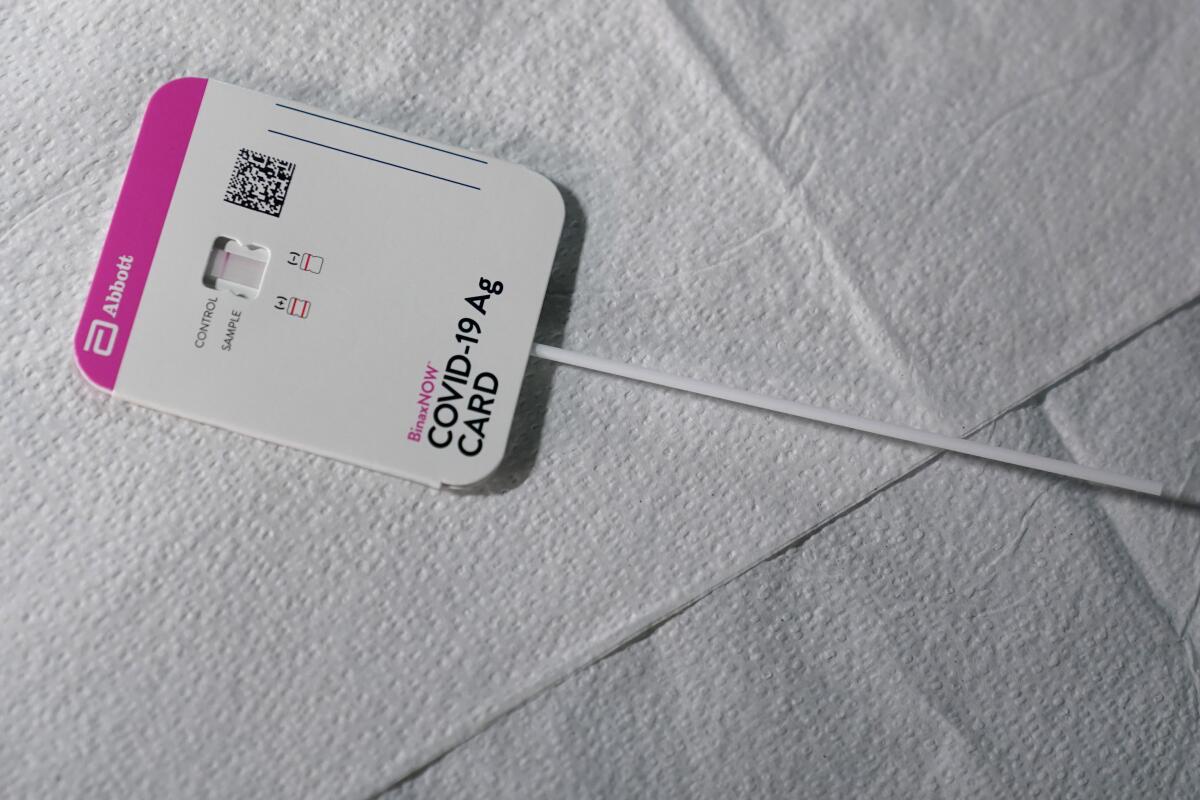 A nasal swab is inserted in a test that says "COVID-19 Ag card."