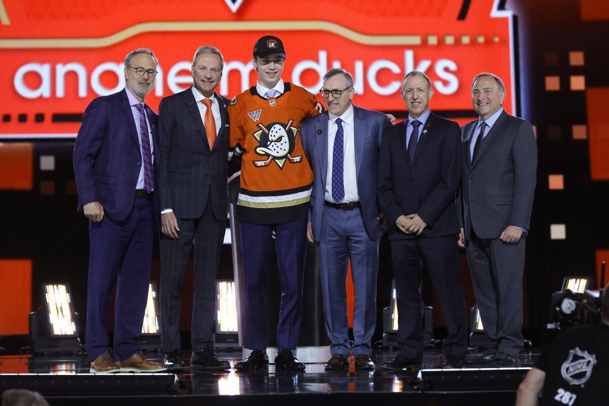 Beckett Sennecke, center left, poses with Ducks general manager Pat Verbeek, third right, team executives.