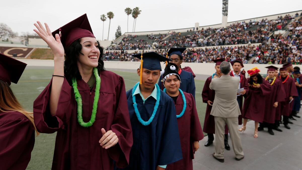 Metropolitan High School student Yesenia Ceballos, 18, waves to family members at a graduation ceremony.