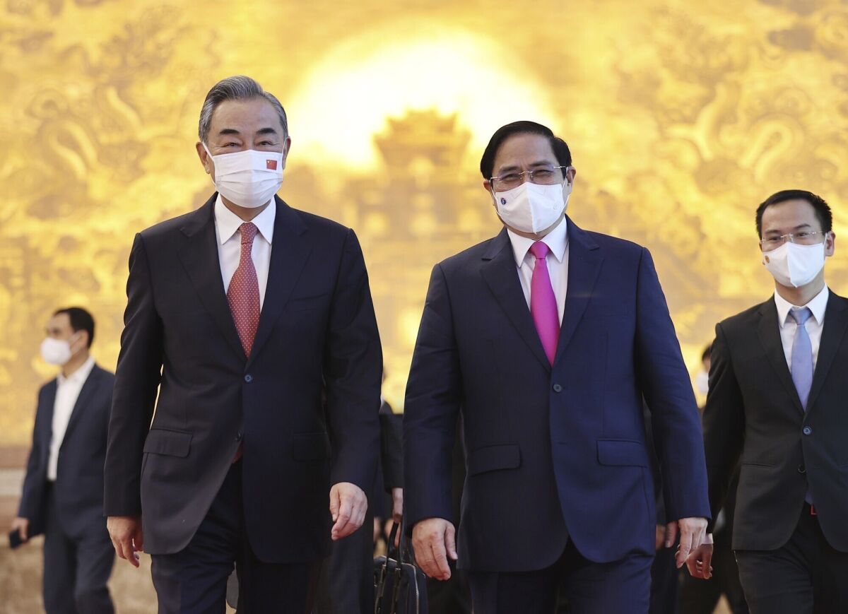 Vietnamese Prime Minister Pham Minh Chinh and Chinese Foreign Minister Wang Yi walk into meeting room in Hanoi, Vietnam on Saturday, Sep.11, 2021. China has pledged to donate 3 million doses of its vaccine to Vietnam as Foreign Minsiter Wang Yi closed his visit to Hanoi. (Duong Van Giang/VNA via AP)