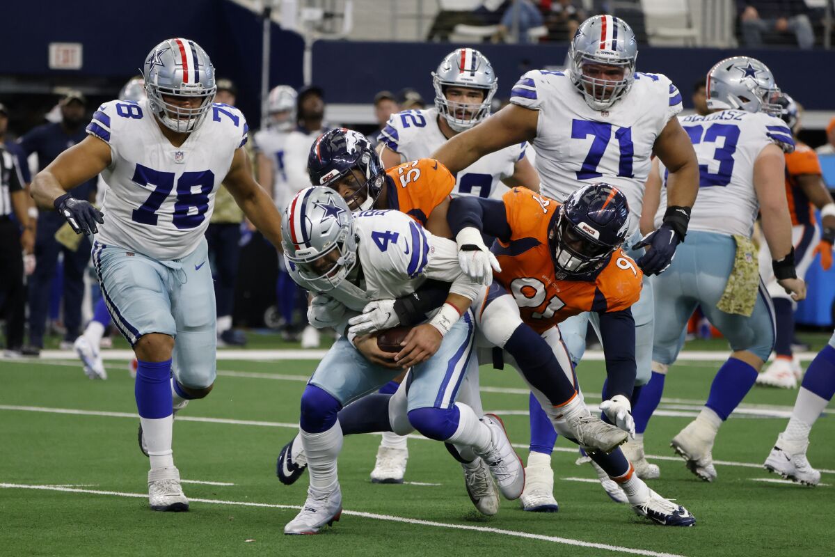 Dallas Cowboys quarterback Dak Prescott (4) is sacked by Denver Broncos' Jonathon Cooper (53) and Stephen Weatherly (91) as Terence Steele (78) and La'el Collins (71) look on in the second half of an NFL football game in Arlington, Texas, Sunday, Nov. 7, 2021. (AP Photo/Michael Ainsworth)