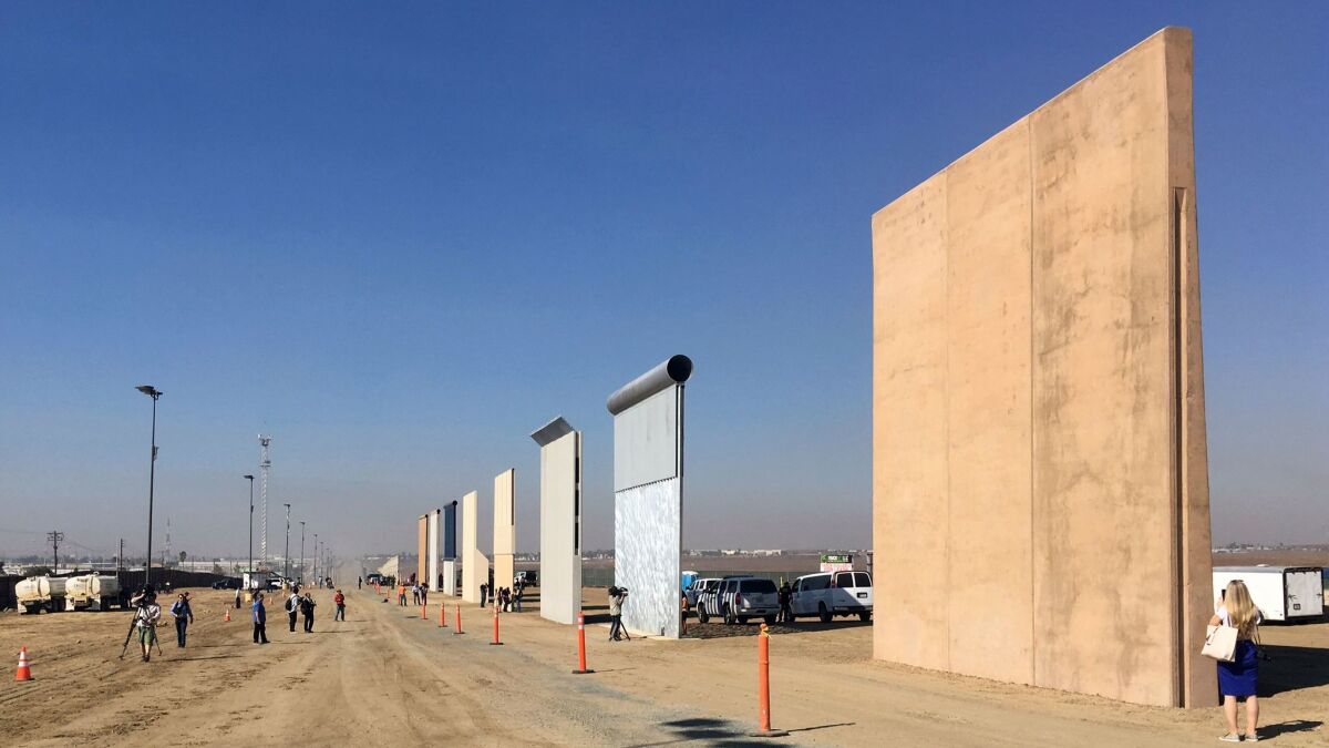 People look at prototypes of a border wall.