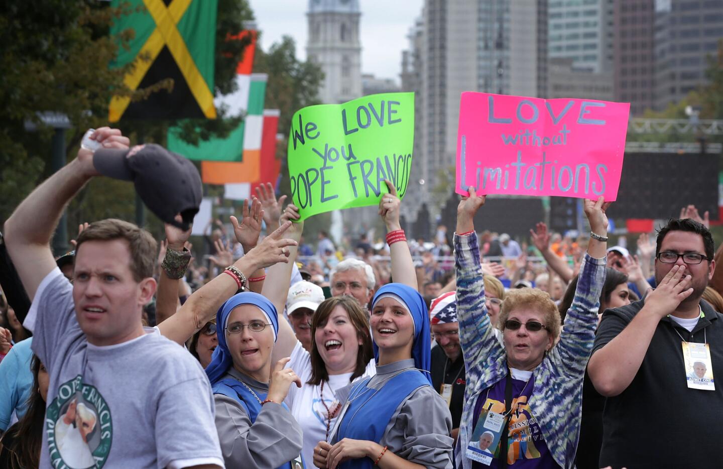 Attendees wave to TV cameras as they wait for the beginning of the mass for the conclusion of the World Meeting of Families on Benjamin Franklin Parkway, Sunday, Sept. 27, 2015 in Philadelphia.