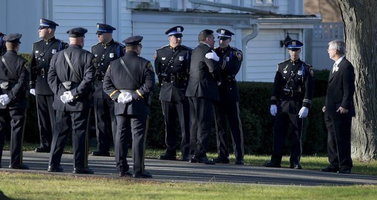 A family member embraces the members of a police color guard before the arrival of the casket at the funeral for Sandy Hook Elementary School teacher Victoria Soto at the Lordship Community Church in Stratford, Conn.